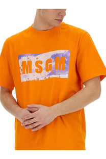 Bright orange MSGM men’s t-shirt with bold rectangular graphic featuring splattered purple and white accents