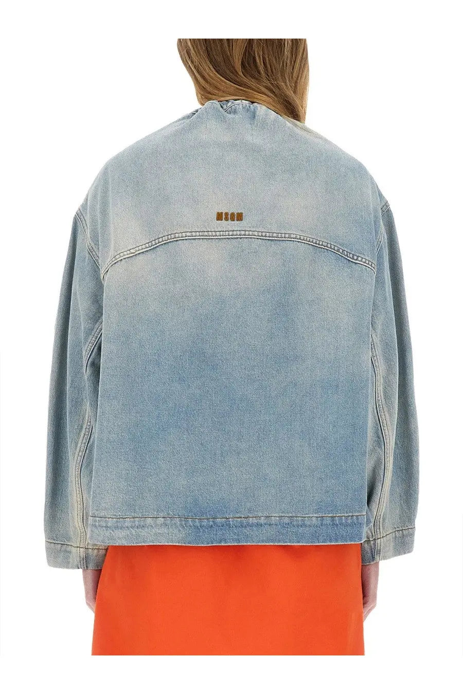 Back view of msgm women’s light-wash denim jacket with subtle faded texture and small brown embroidered logo