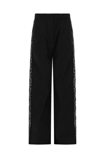 Black wide-leg MSGM womens trousers with shimmering silver sequin side stripes and lace detailing