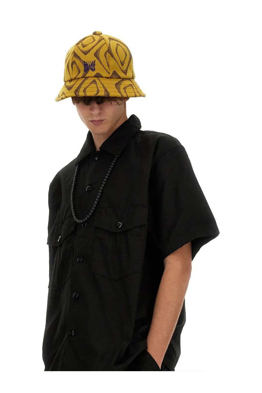 Yellow bucket hat with brown geometric pattern and purple butterfly emblem paired with needles men’s black cotton shirt
