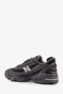 New Balance men’s low top black sneaker with dark gray mesh and synthetic leather upper and white branding accents