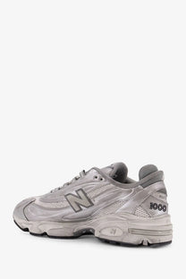 New Balance men’s low top silver sneaker with distressed finish and mesh synthetic overlays
