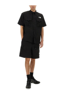Black short-sleeved button-up shirt with two chest pockets and white north face logo on left breast