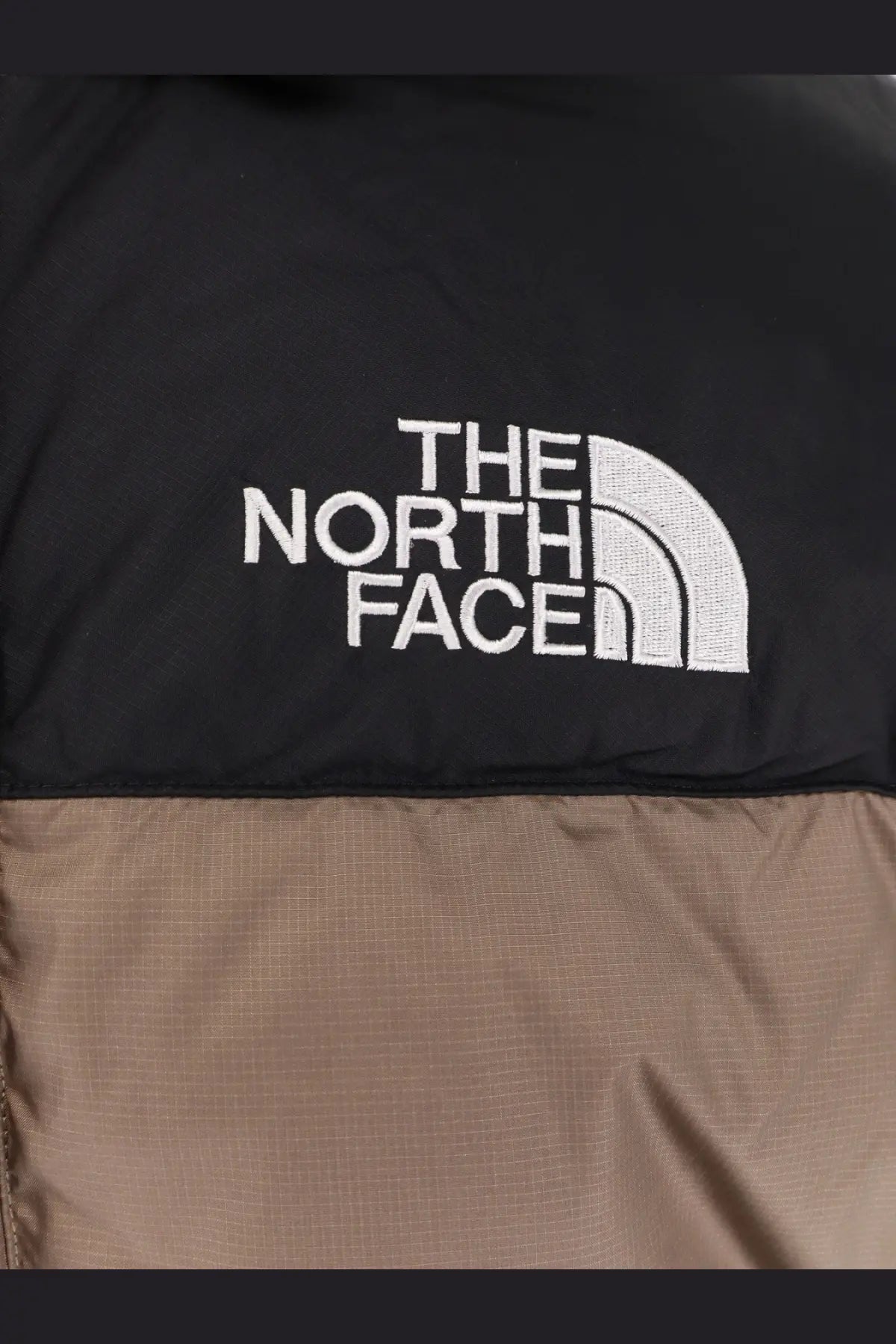 The north face men’s himalayan nylon down jacket in black and tan with white embroidered logo is a puffer style