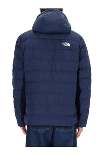 The North Face men’s dark blue quilted puffer jacket with hood shown from the back featuring the logo on upper back