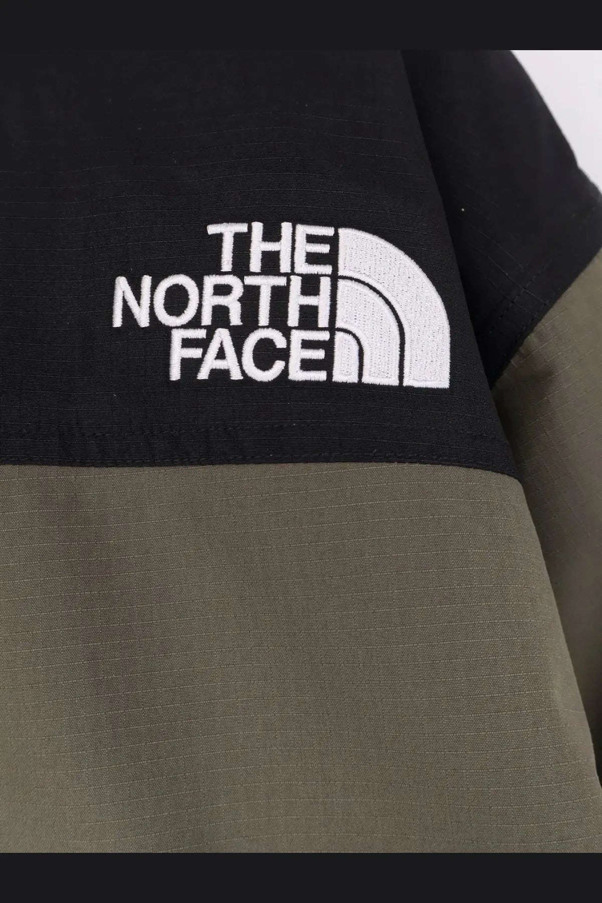 The North Face men’s mountain down jacket in black and olive green with a white embroidered logo on the sleeve