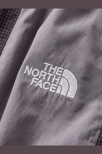 Gray north face jacket with white embroidered logo paired with black nylon bermuda shorts for men