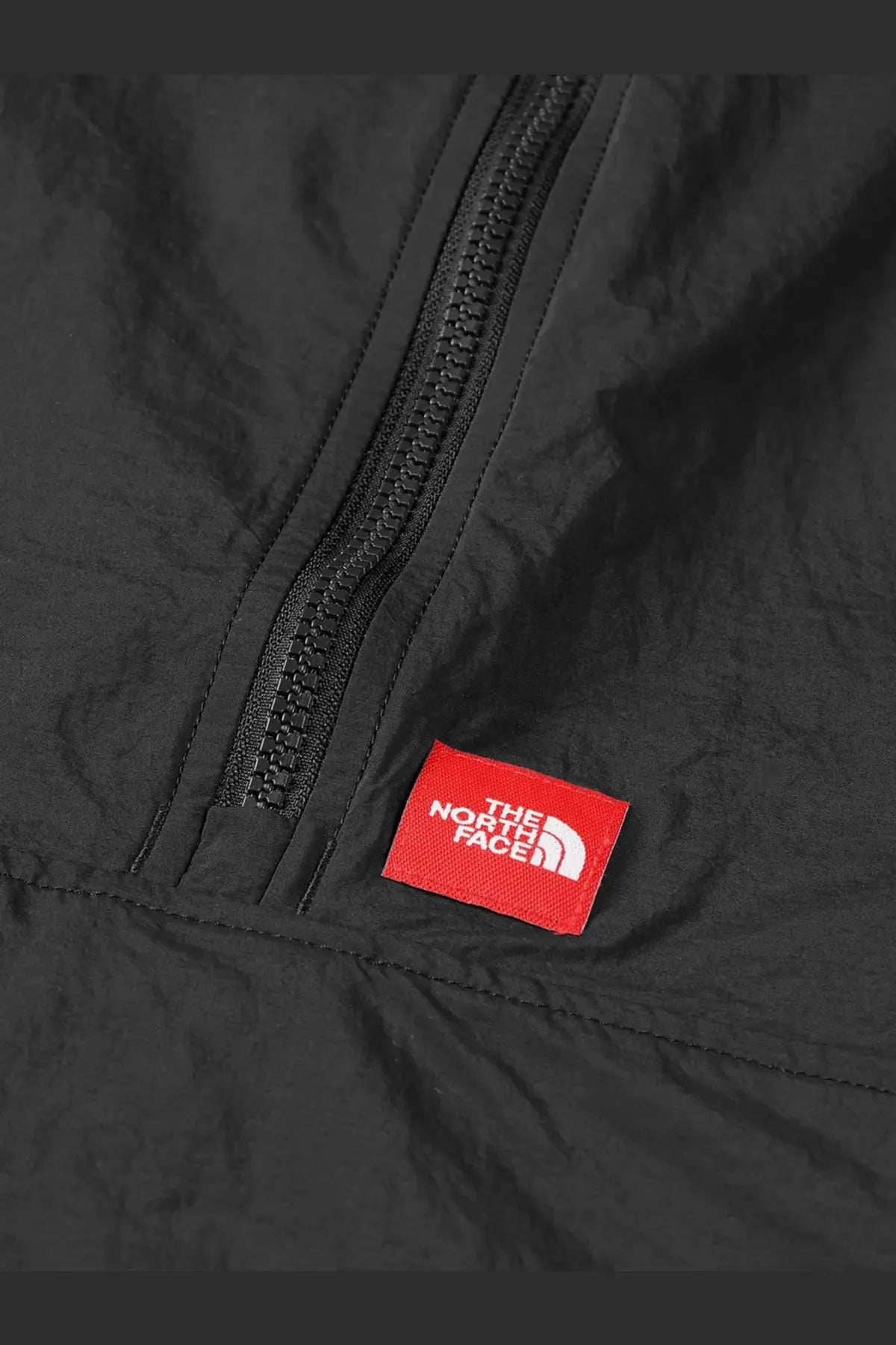 The north face men’s black nylon jacket with a red rectangular logo label and white text on the front