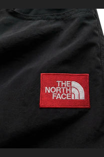 Black the north face patch with red border and white logo on the front of the north face men’s black nylon trousers