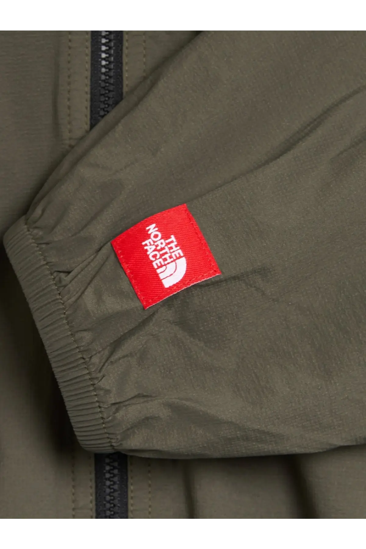 Olive green nylon sleeve with red the north face tag on the men’s packable nylon jacket beige product