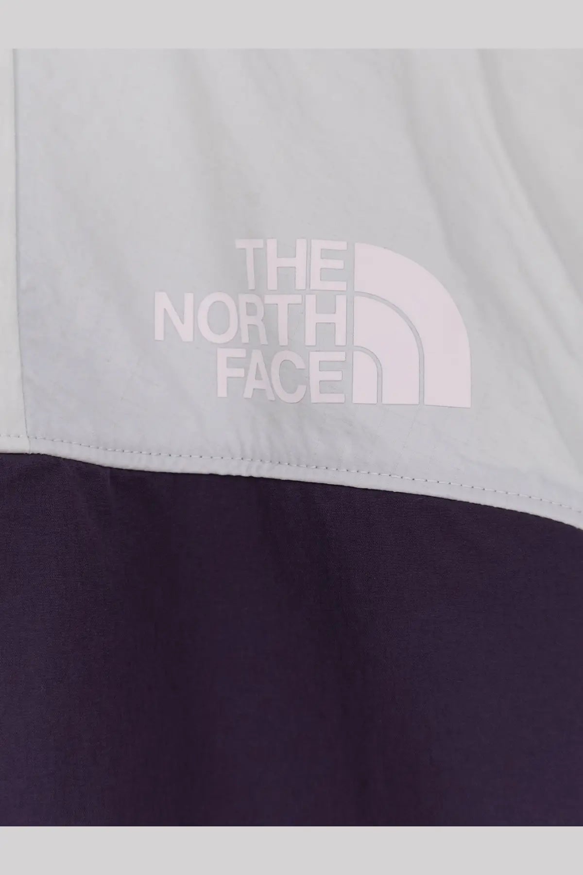 The north face men’s relaxed fit jacket white with a white logo patch on a two-tone light gray and navy jacket