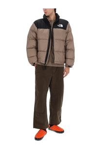 The North Face men’s retro Nuptse jacket in brown tan and black features a quilted puffer design for warmth