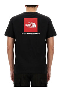 The North Face men’s black short-sleeved shirt features a bold red square logo and never stop exploring text