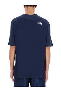 The back side of a navy blue The North Face men’s short-sleeved shirt with a white logo on the upper back