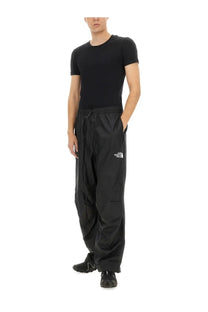 Black the north face men’s wind track cargo pants with drawstring waist and white logo on thigh in nse black color