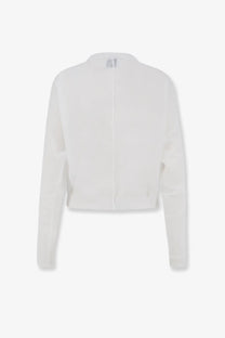 White cropped knit cardigan with long sleeves and central zipper paired with nude women’s cotton blend polo shirt white