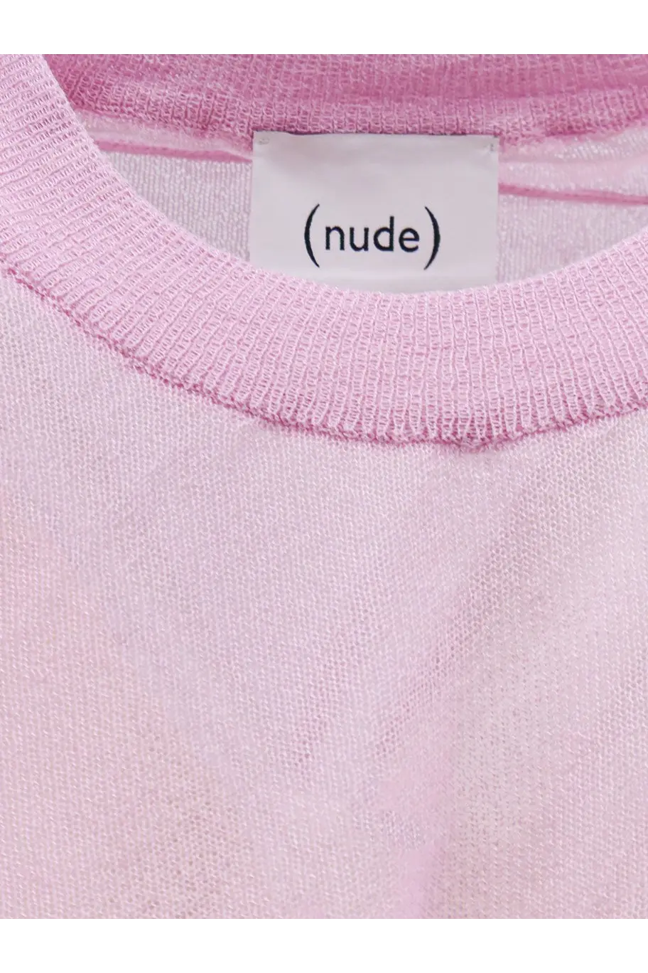 A soft pink nude women’s cotton blend shirt featuring a ribbed neckline and a white label on the front