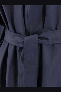 Dark navy belted coat with matching fabric belt tied in a neat knot over nude womens cotton dress blue
