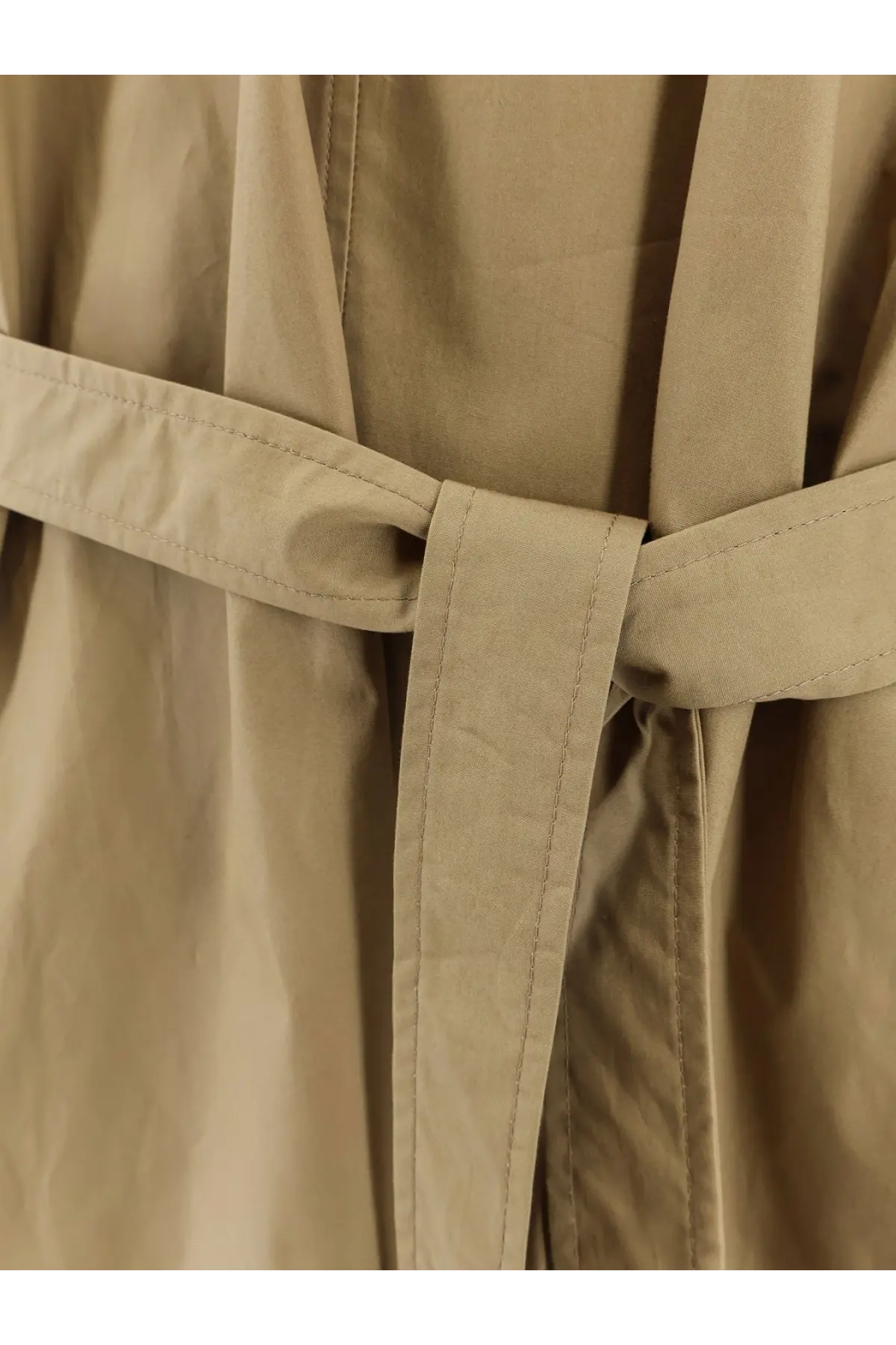Beige trench coat belt with neat stitching and tied knot paired with nude women’s cotton dress green