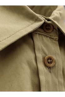 Beige button with mille engraving on khaki fabric collar of nude women’s green cotton shirt