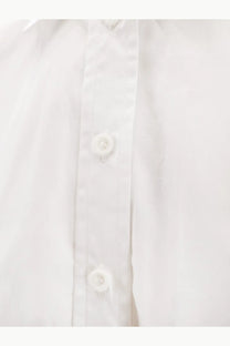 Nude women’s white cotton shirt with crisp fabric and matching white buttons along the front placket