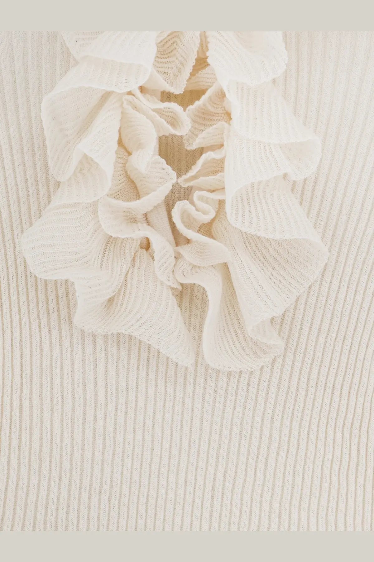 A delicate off-white ruffled detail on a nude women’s ribbed cotton blend sweater in white