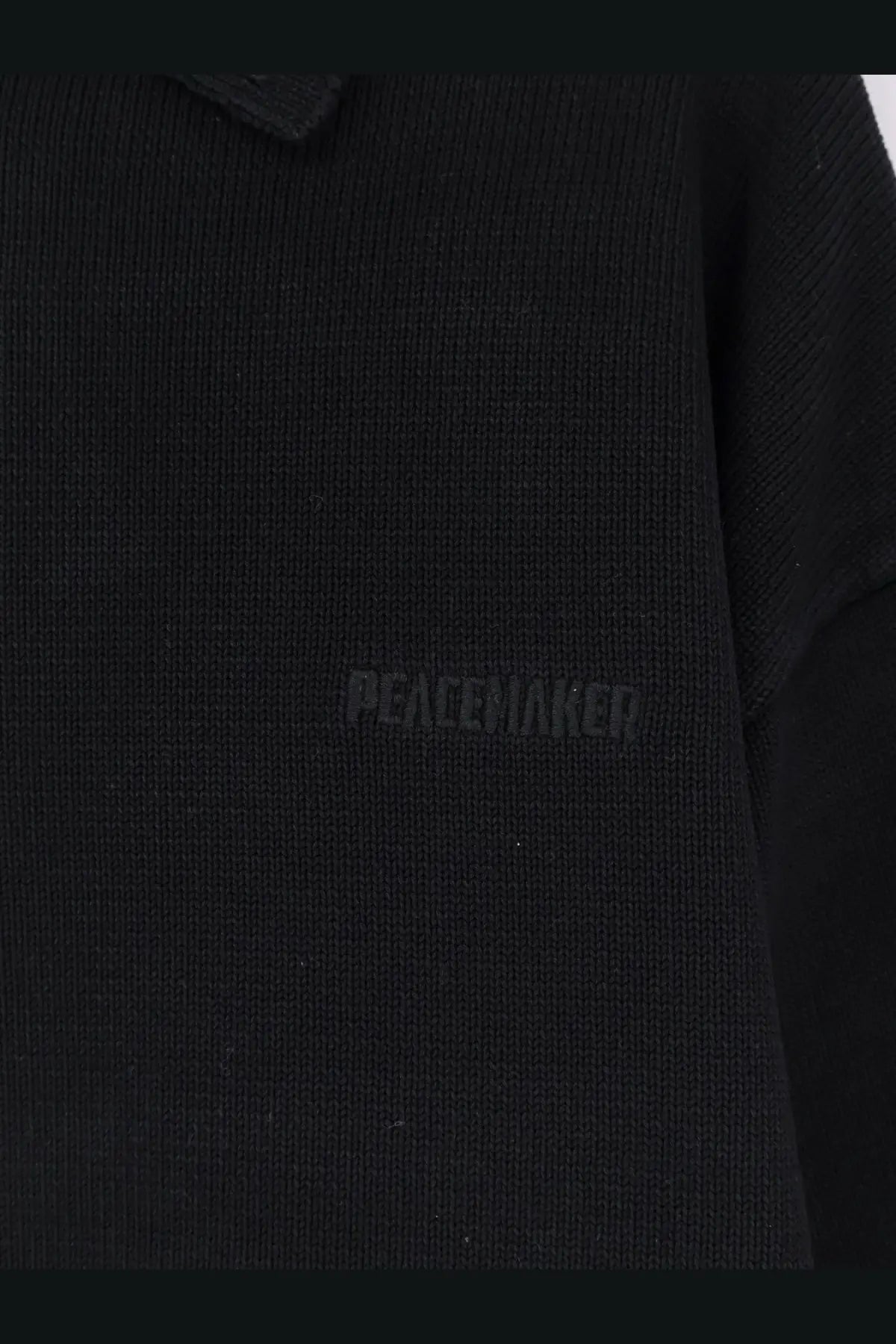 Black knitted cotton Oamc peacemaker men’s polo shirt with subtle peacewaker embroidery on the chest