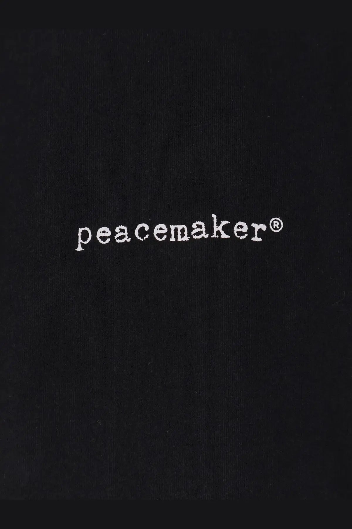 Black fabric tote bag with white peacemaker logo embroidered in sans serif font for oamc peacemaker men’s cotton shirt black