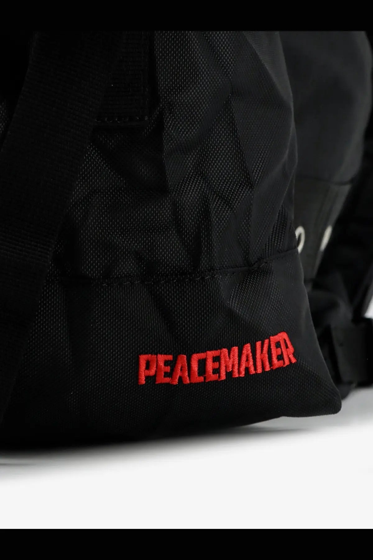Black nylon Oamc Peacemaker men’s jungle backpack with bold red embroidered peacemaker branding
