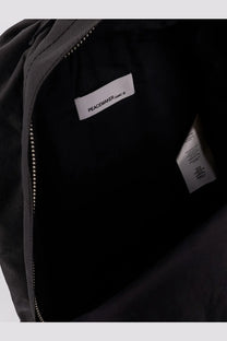 Black oamc peacemaker men’s nylon backpack interior showing white brand label and durable fabric lining