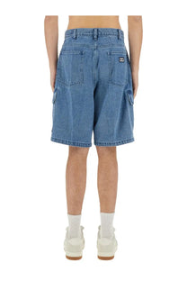 Back view of obey men’s baggy bigwig blue denim cargo shorts with pockets and brand logo on the right pocket