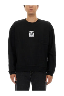Obey men’s black cotton crewneck sweatshirt with a white embroidered face logo on the chest