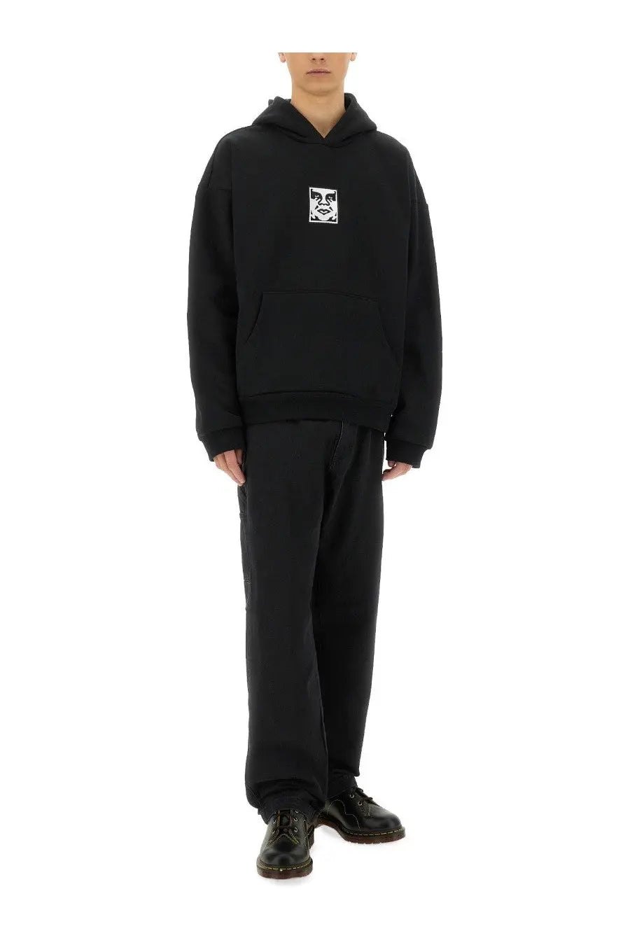 Black oversized hoodie with white graphic patch on chest styled with obey men’s hardwork jeans blue