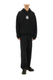 Black oversized hoodie with white graphic patch on chest styled with obey men’s hardwork jeans blue