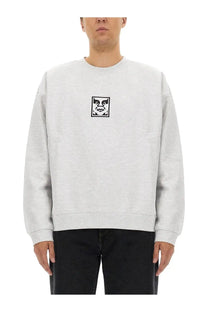 Obey men’s light gray crewneck sweatshirt with black and white stylized face graphic on chest