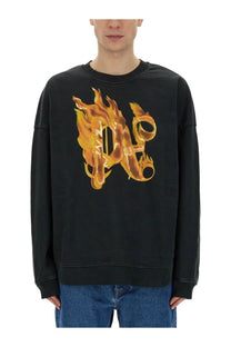 Black oversized Palm Angels men’s sweatshirt with bold flame-embossed d logo in golden-orange hues across the chest