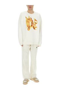 Off-white long-sleeved Palm Angels sweatshirt with a bold golden-orange flame monogram print on the chest
