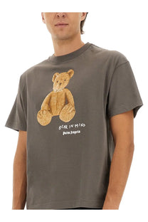 Palm Angels men’s grey t shirt with textured gold bear graphic and bear in mind palm angels text printed below