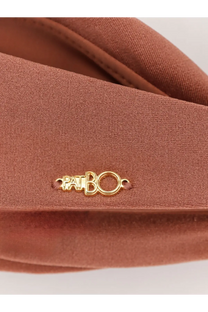A tan leather crossbody bag with a gold tone patti bo logo plaque shown with patbo women’s orange lycra bikini top