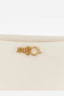 Gold-tone metal patbo logo charm on white nylon patbo women’s bikini bottoms front view