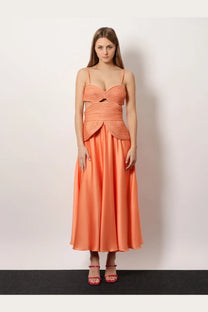 A woman wearing a coral patbo women’s satin sunset midi dress with a woven bodice and flowing satin skirt