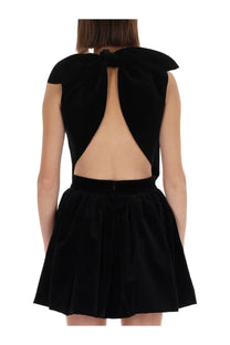 Back view of patou women’s black velvet mini dress with large bow and open-back design