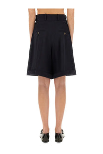 Black high-waisted Patou women’s wool Bermuda shorts with tailored fit gold button back pockets and rolled cuffs back view