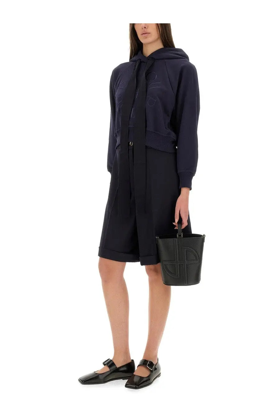 Black leather bucket bag with embossed geometric logo paired with Patou women’s blue wool Bermuda shorts