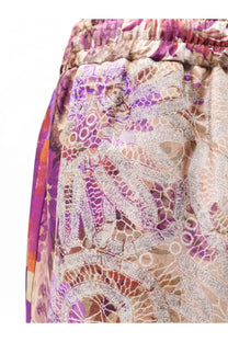 A pair of pierre-louis mascia high-waisted silk shorts with a vibrant abstract pattern in purples oranges and beige