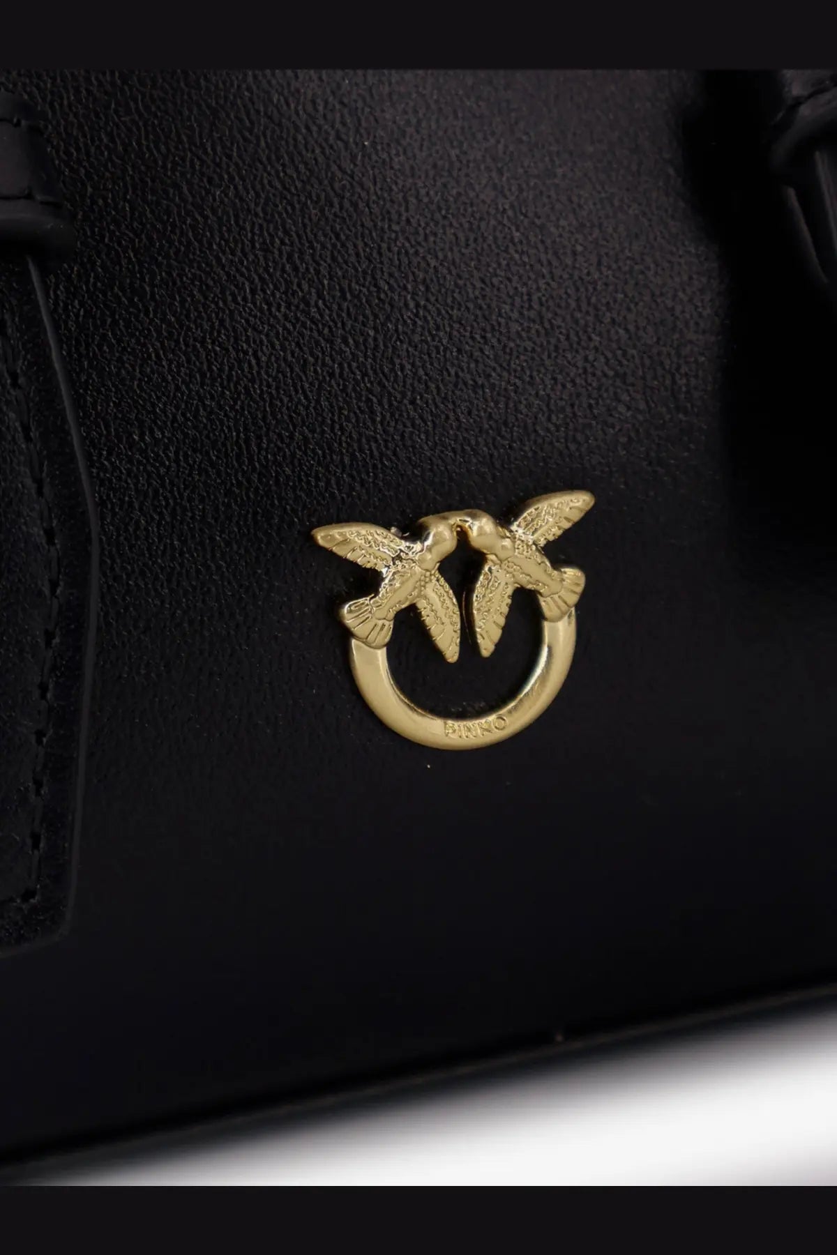 Pinko women’s black leather handbag featuring a gold-tone clasp with two stylized birds on a circular ring