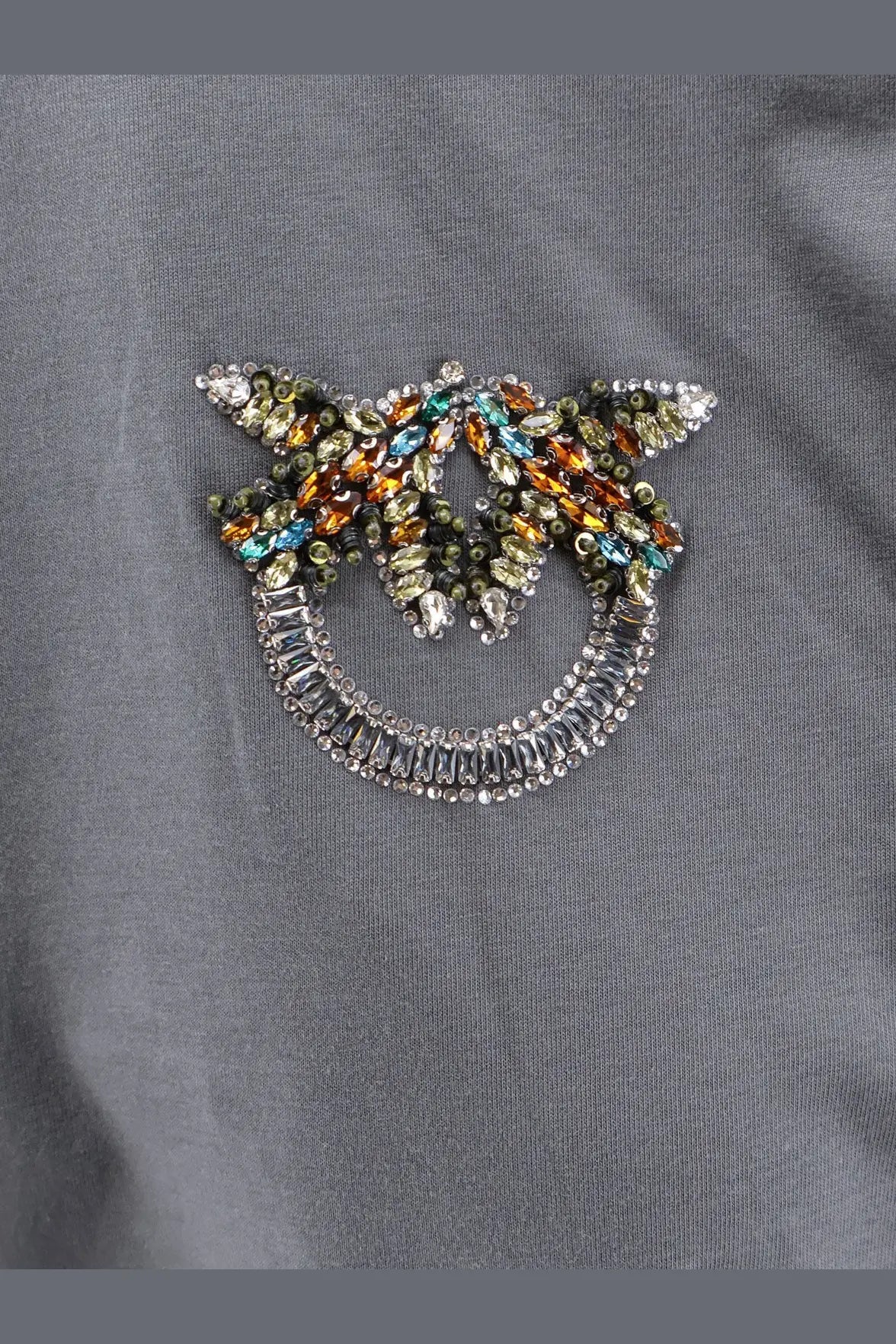 Pinko women’s grey cotton shirt featuring a sparkling multicolored rhinestone smiling face brooch with wing extensions