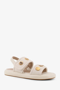 Cream-colored pinko women’s fiona low leather sandals with gold-tone circular studs and logo emblem on strap