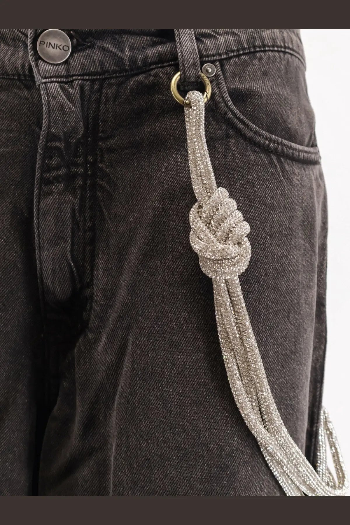 A sparkling silver beaded chain with a knotted design attached to black pinko women’s lauryn bull denim jeans