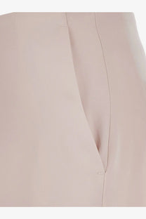 A close-up of pinko women’s limoncello satin trousers in pale pink fabric with subtle vertical stitching and gentle folds